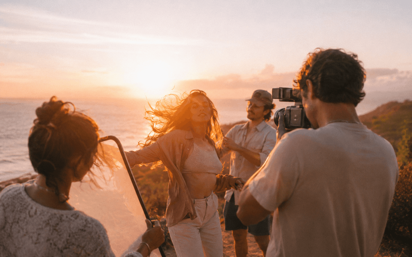 Kreatives Team beim Content-Shooting am Meer im Sonnenuntergang